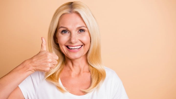 woman over 50 with long blonde hair giving thumbs up