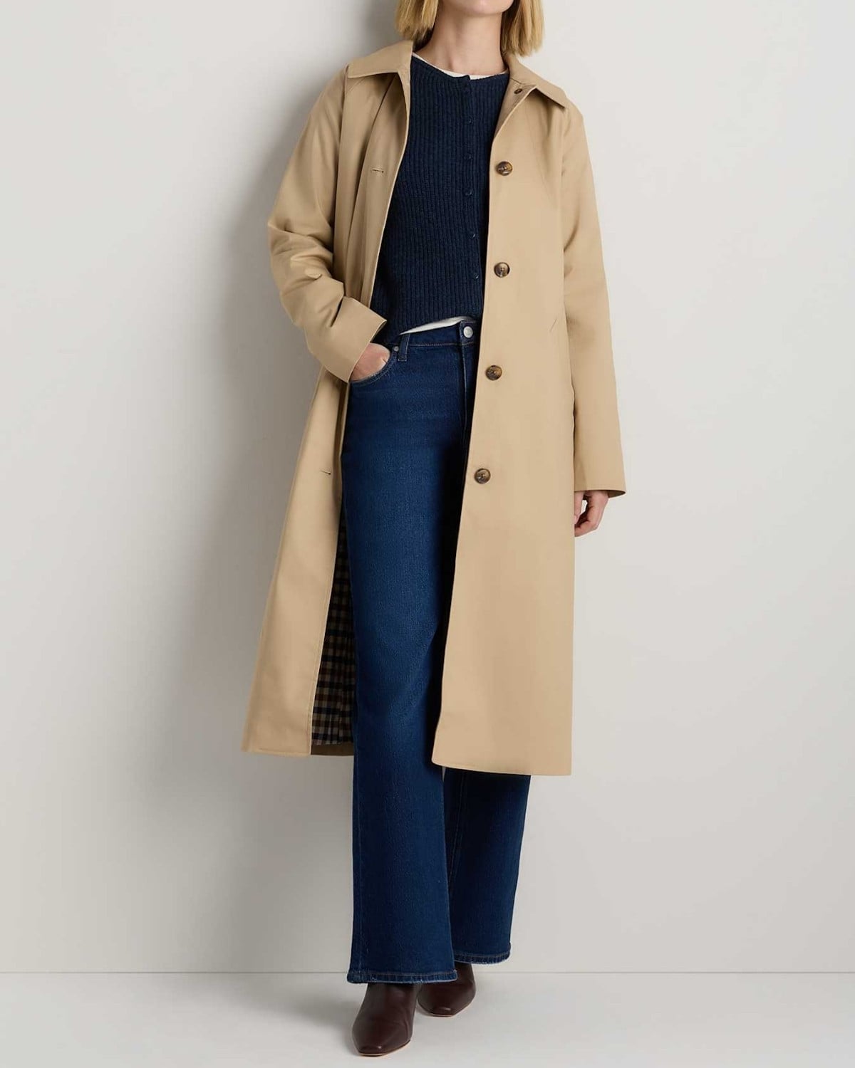 Classic trench coat layered over a sweater with straight-leg jeans and ankle boots for a fall outfit in New York City.