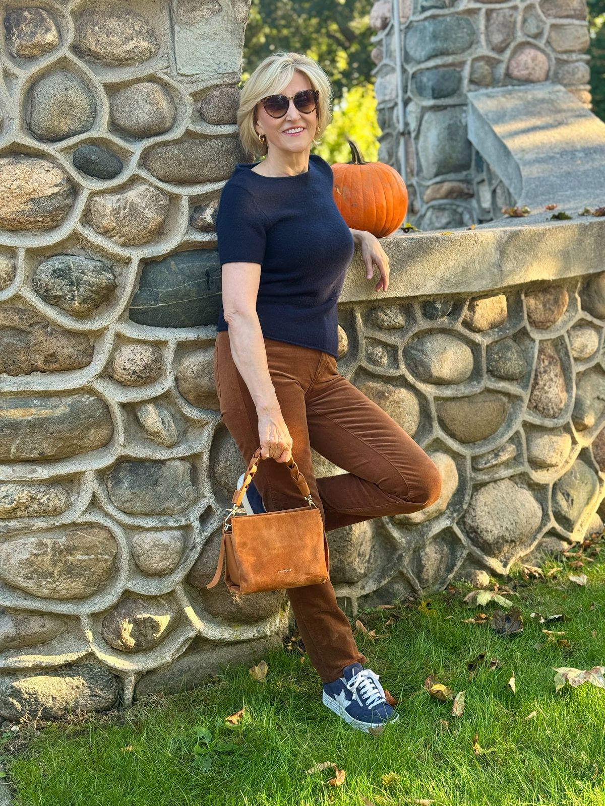 Deborah Boland wearing brown straight leg corduroy pants and short sleeve navy cashmere top and navy sneakers.