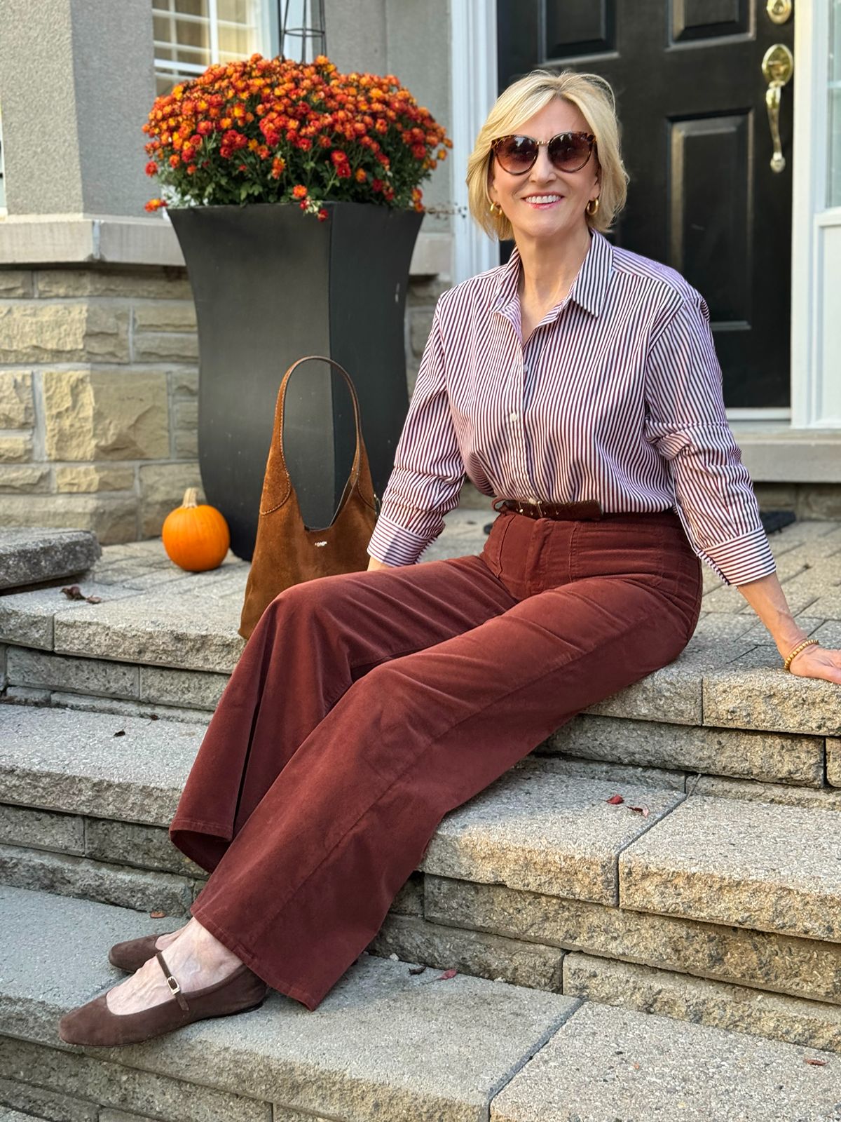 Deborah Boland wearing rust wide leg corduroy pants with , brick striped shirt and mary jane flats.