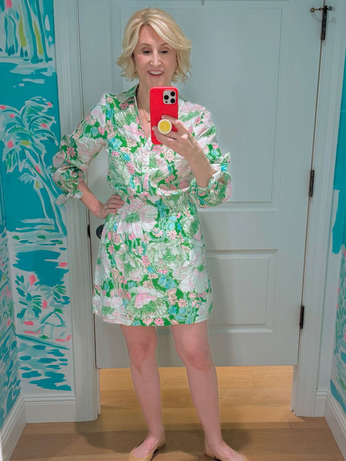 Deborah Boland wearing a colorful Poppyland print fit and flare shirtdress with a structured collar and button down front during a fitting room try on.