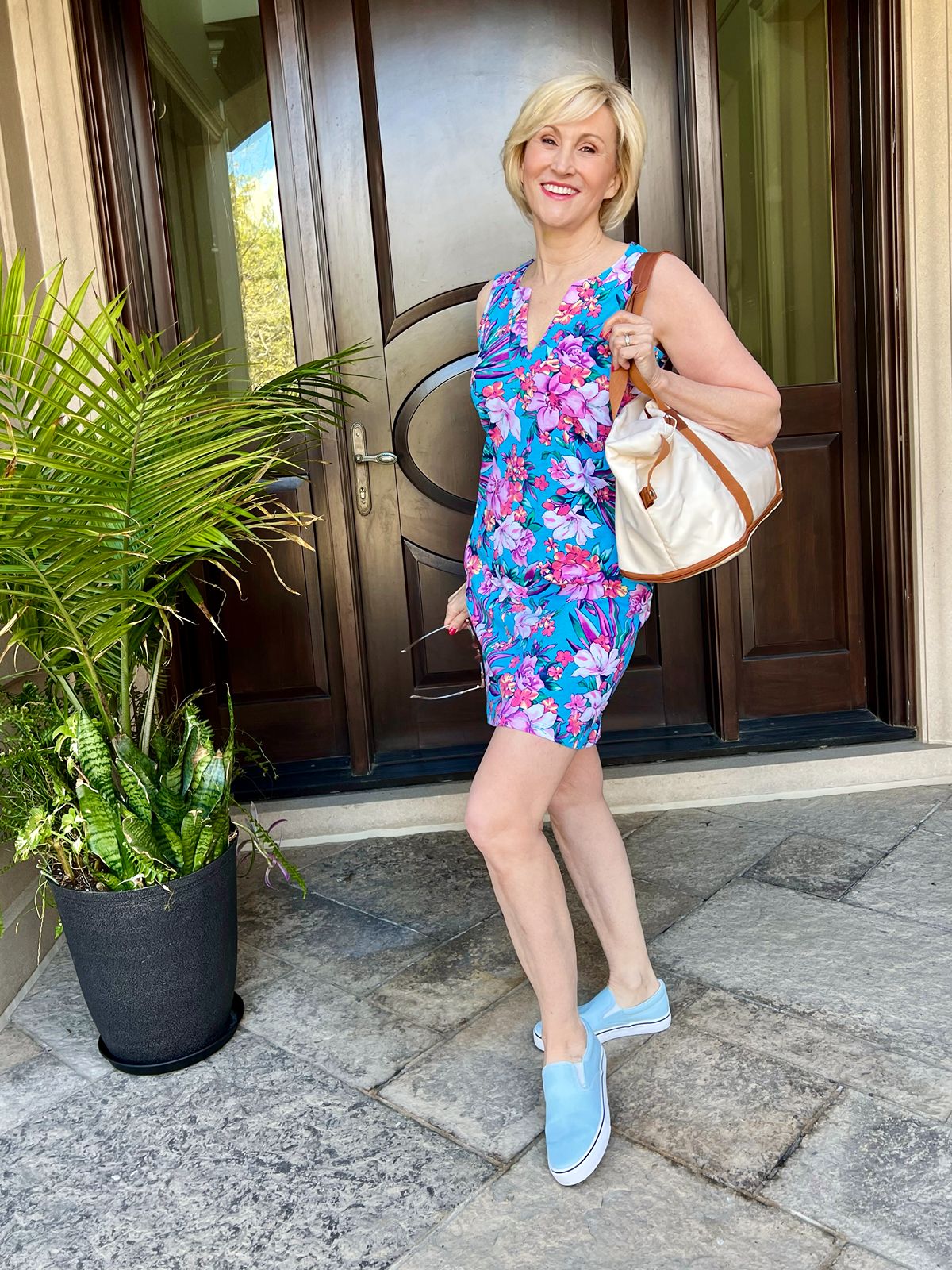 Deborah wearing a colorful floral dress with light blue slip on sneakers for a relaxed summer outfit