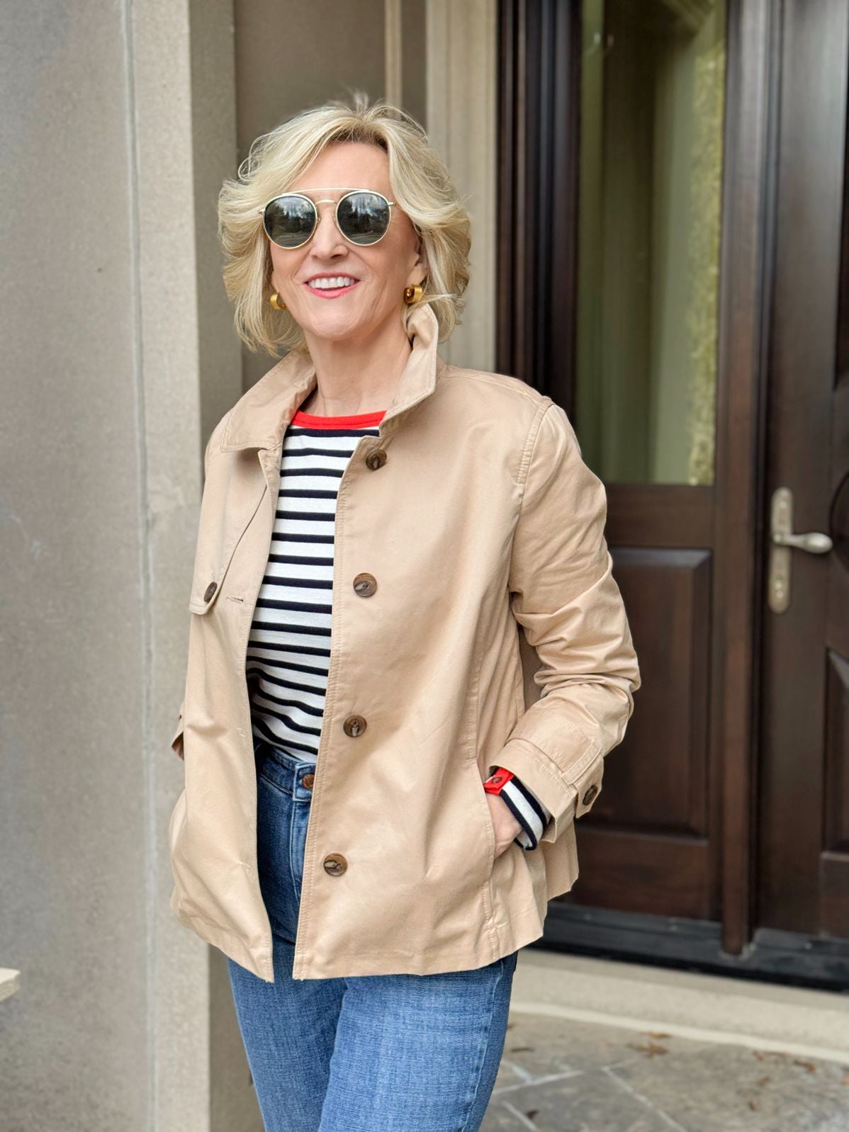 Deborah Boland wearing a striped top, cropped trench jacket, and straight-leg jeans as a classic spring outfit for New York City.