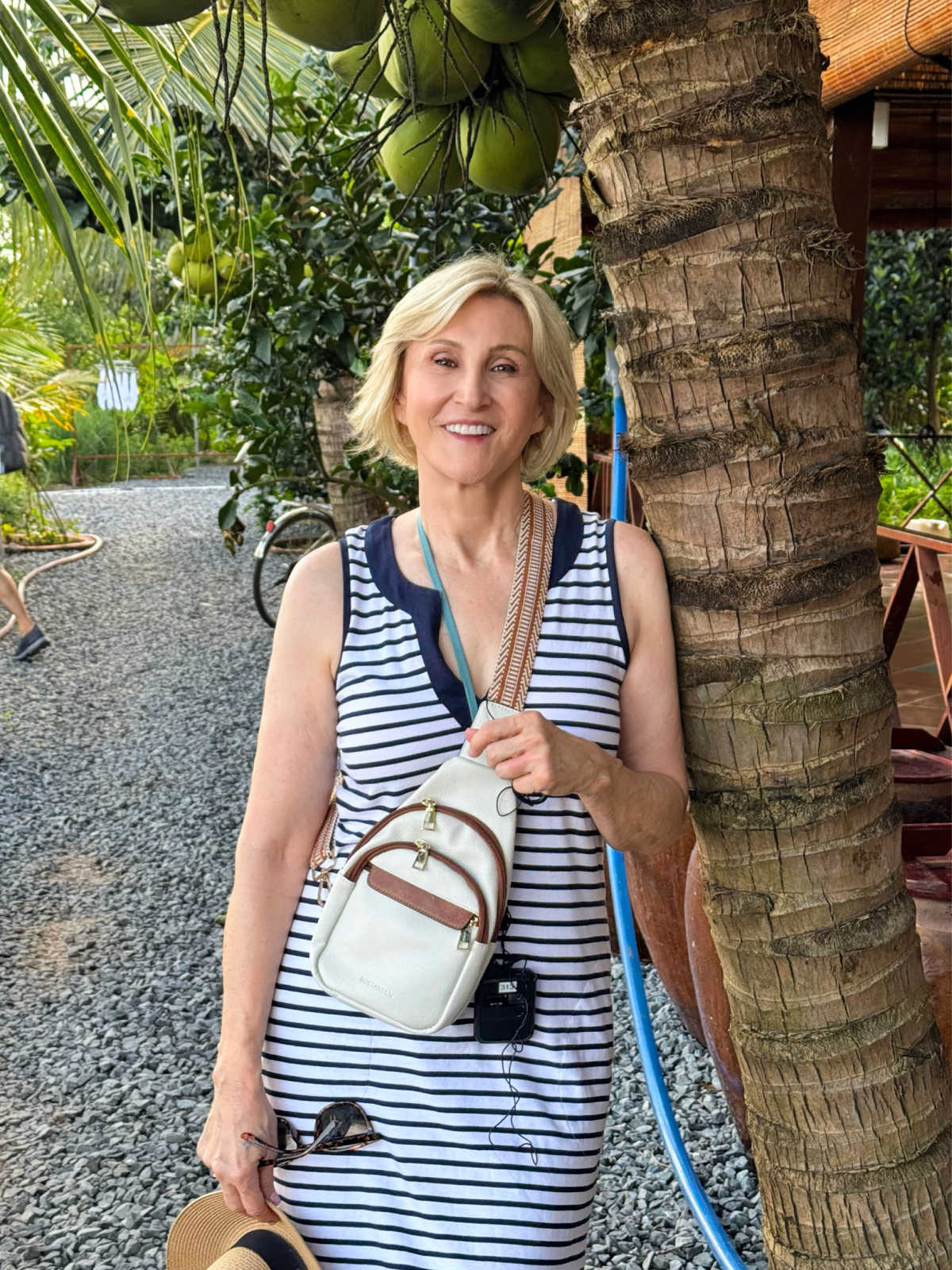Deborah Boland wearing a white crossbody travel bag with a striped dress while sightseeing on vacation.