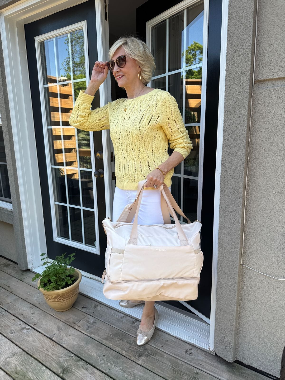 Deborah Boland holding a cream travel duffel bag, a stylish personal item for flights and weekend getaways.