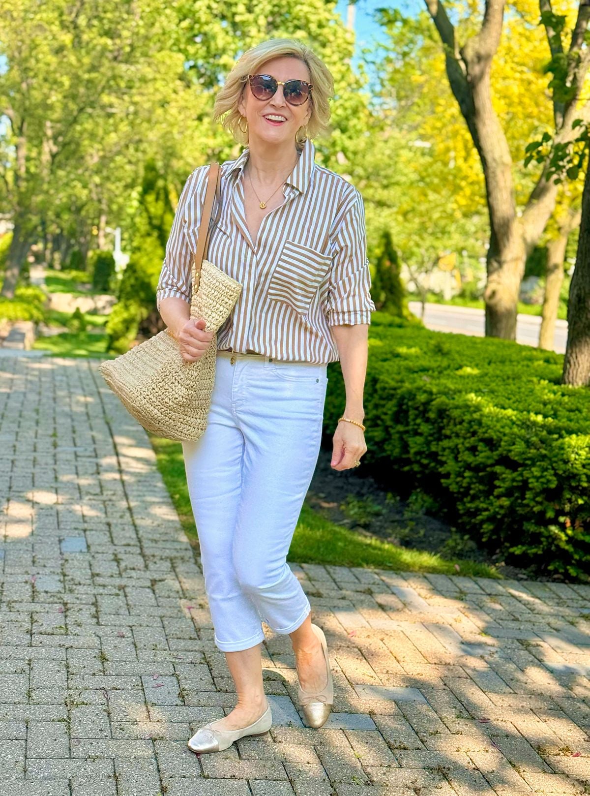 Deborah Boland wearing white cropped pants with a striped button-down shirt for a classic summer outfit without shorts