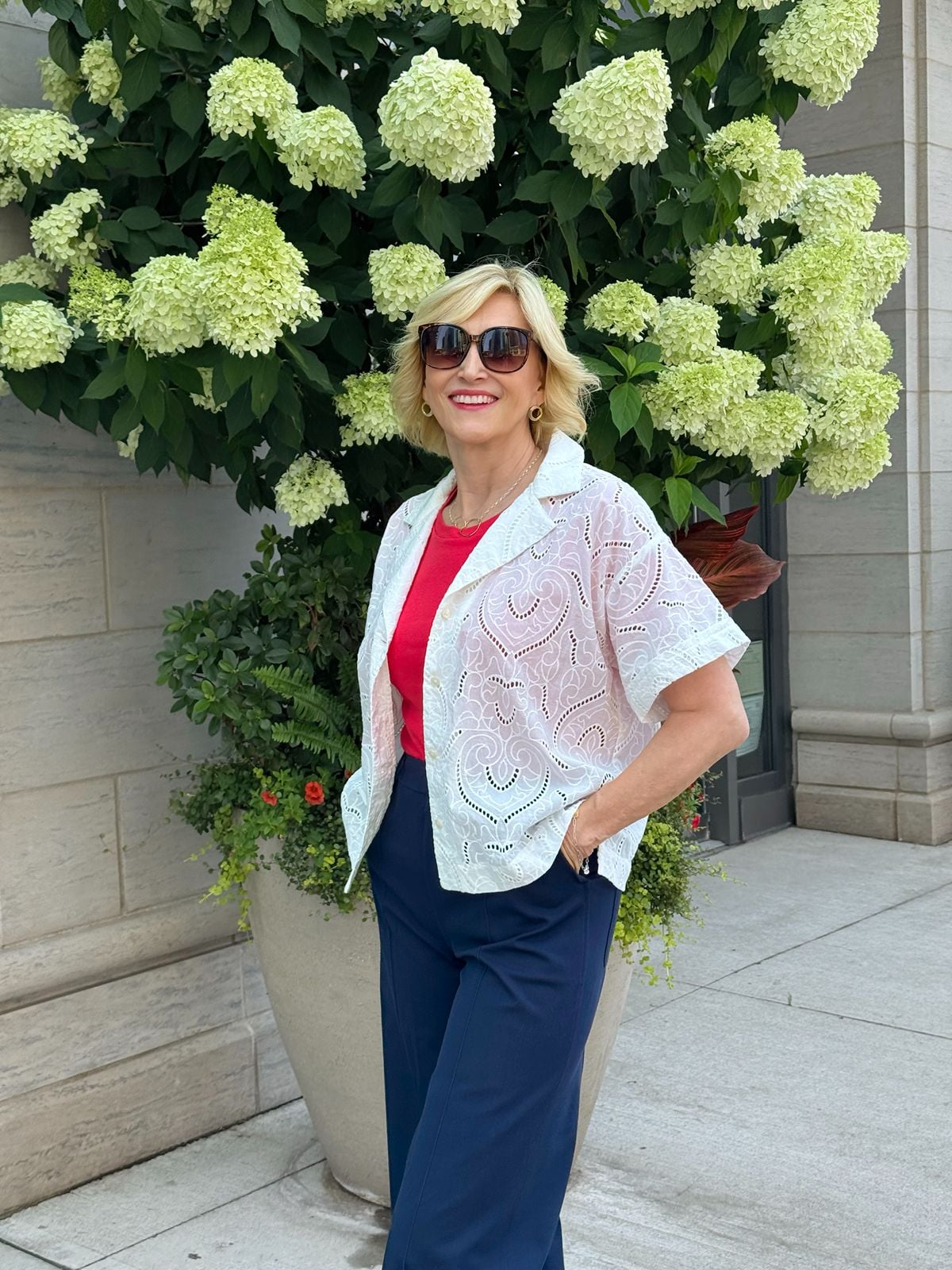 White eyelet shirt for women styled with navy pants and a red tank