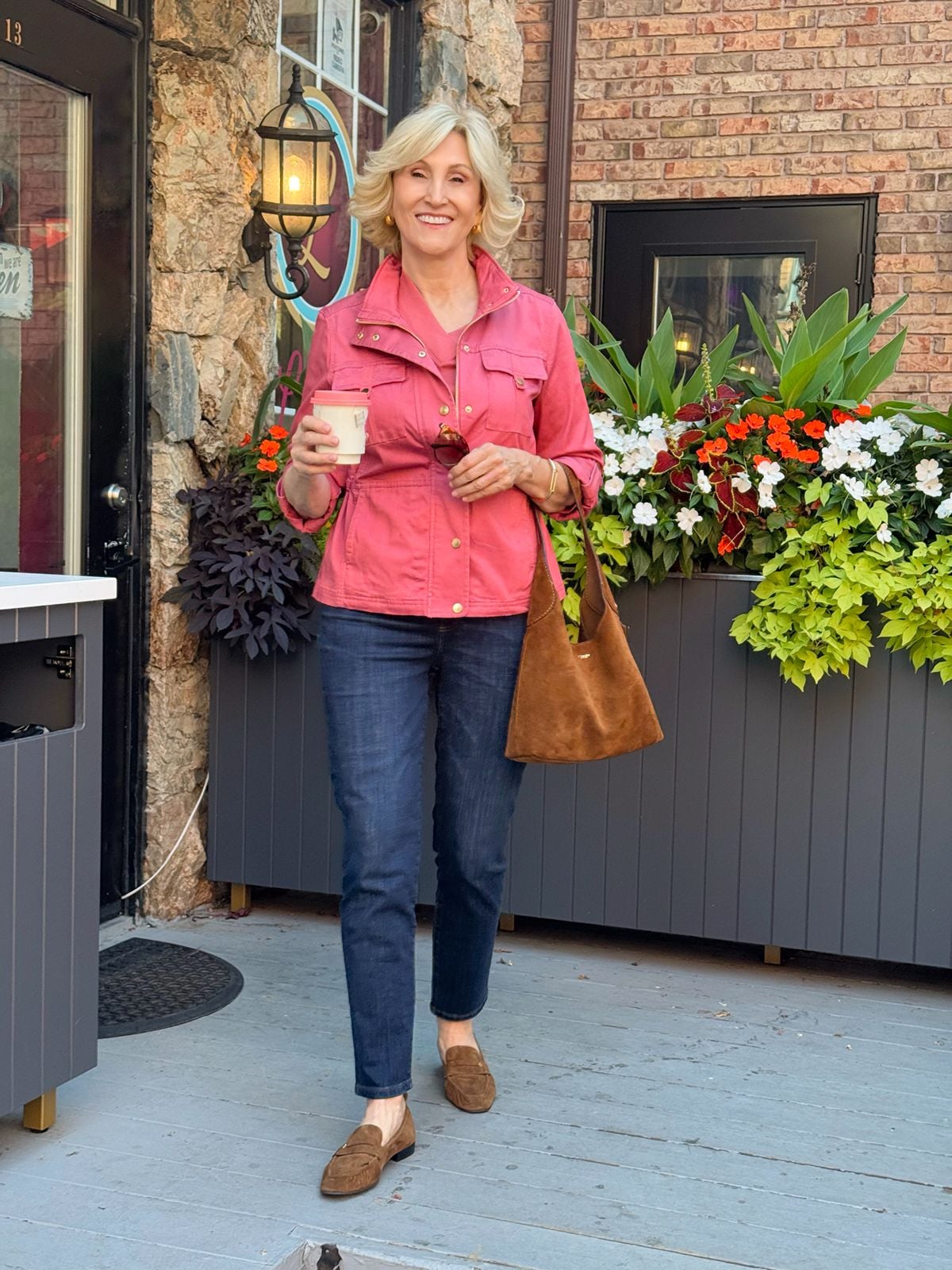 Dark wash slim ankle jeans outfit for women over 50 with a pink jacket and brown suede loafers