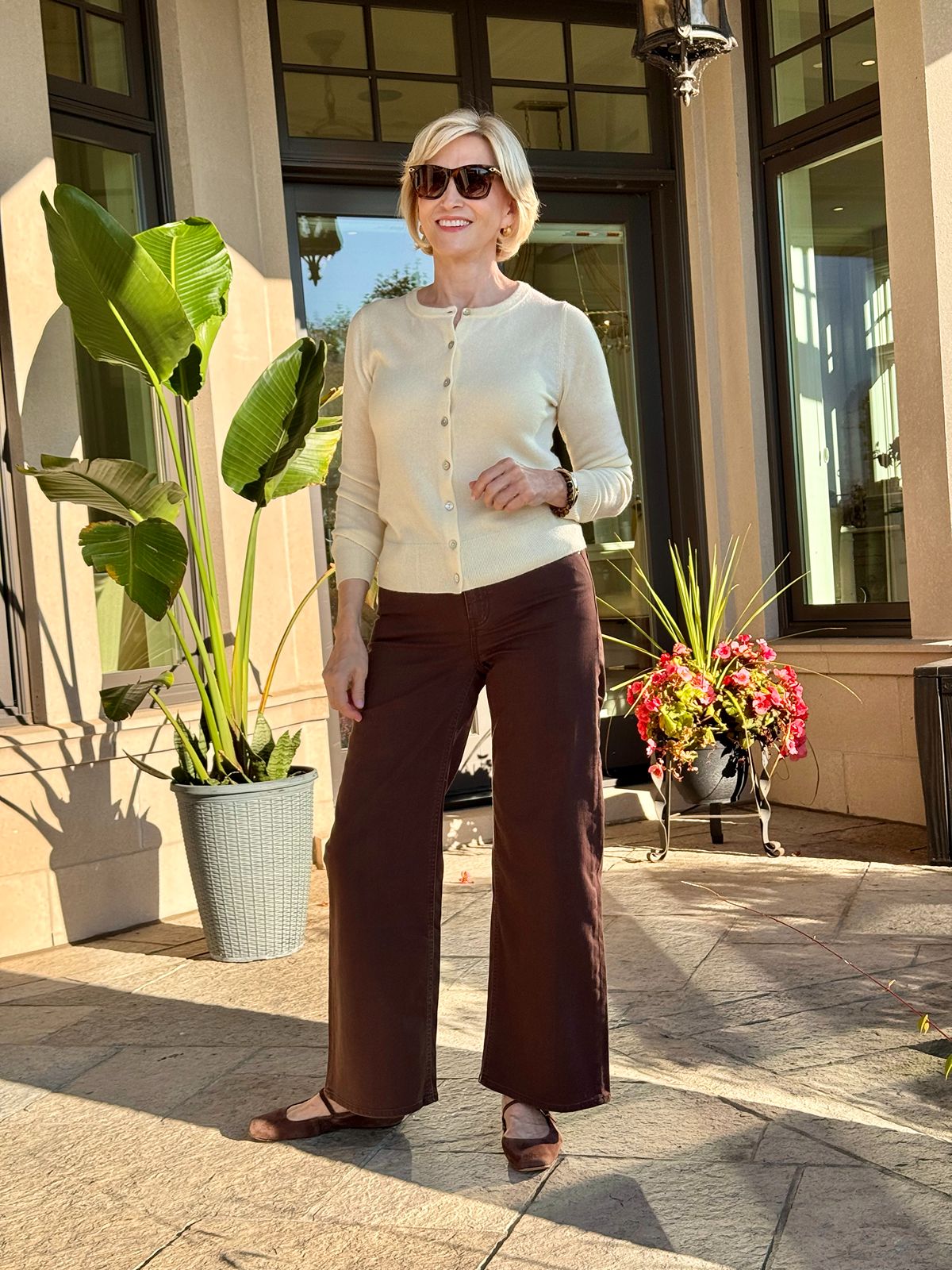 Deborah Boland wearing chocolate brown wide-leg jeans with a cream cardigan and brown suede flats