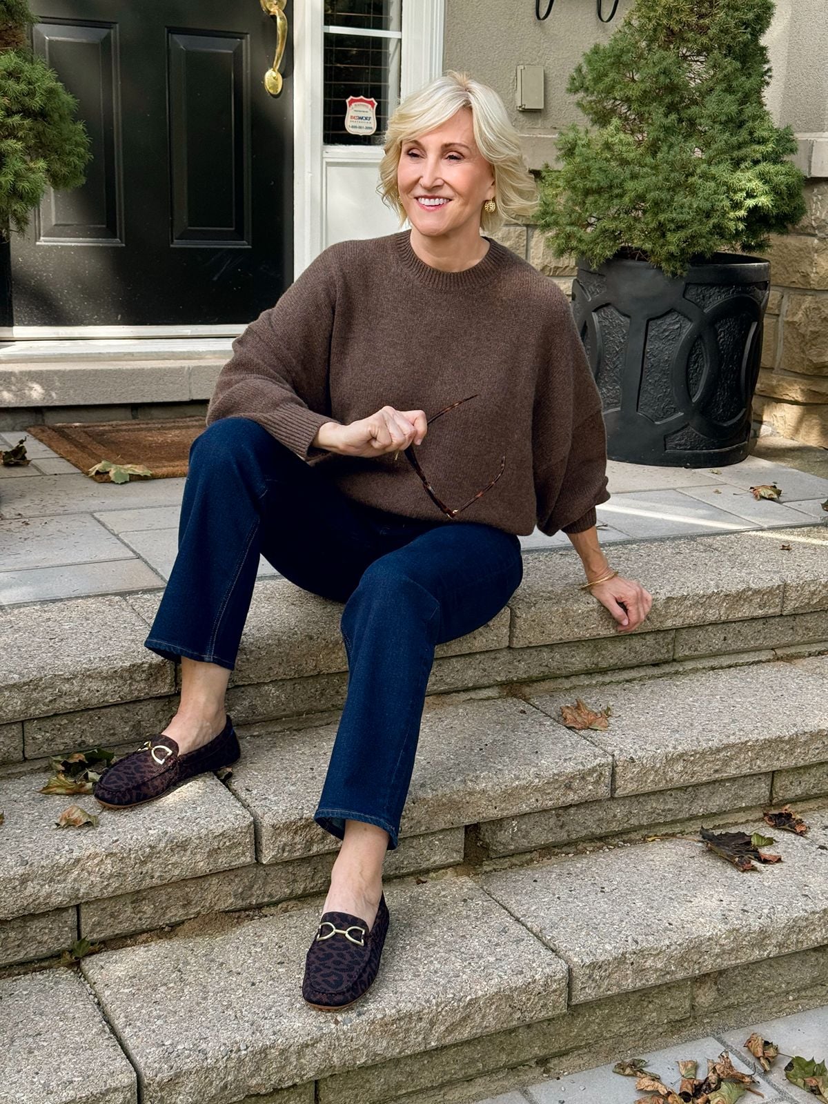Deborah Boland wearing a chocolate brown sweater with dark wash jeans and leopard print loafers