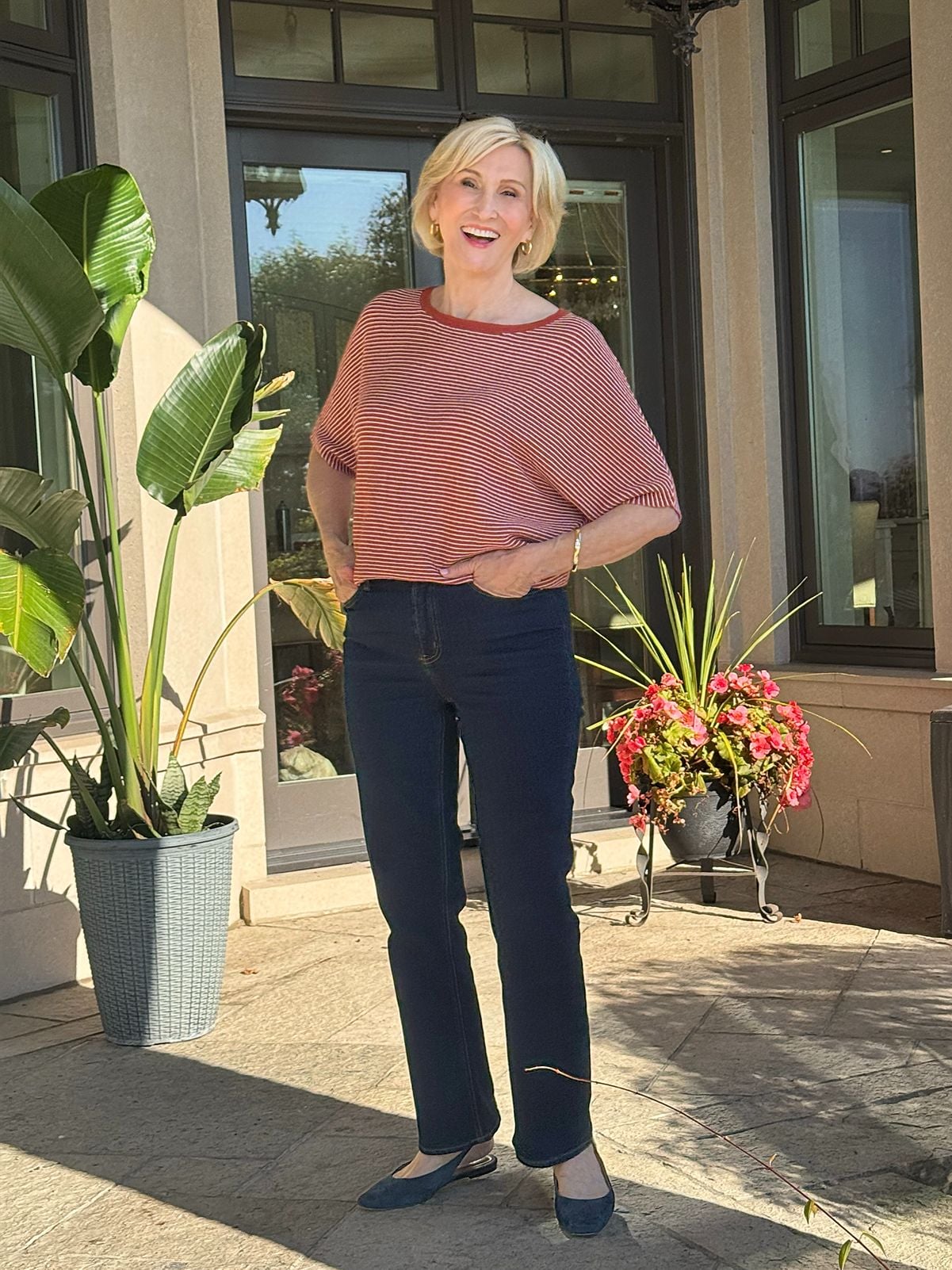 Dark wash straight-leg jeans outfit with a rust striped top and blue flats for women over 50