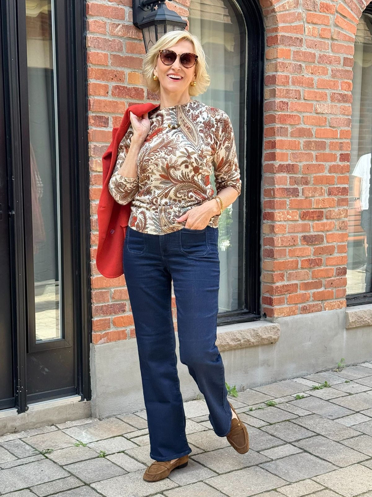 Dark wash bootcut jeans outfit for women over 50 with a paisley sweater and brown suede loafers